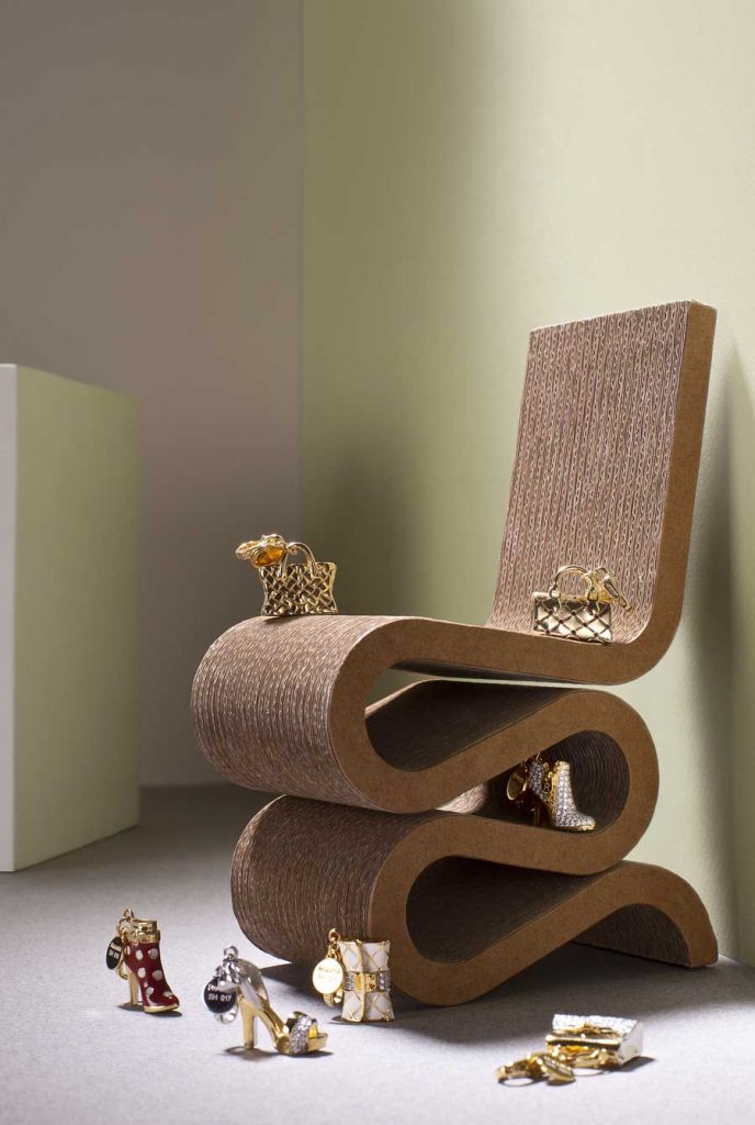 Rosato. Charms in 18kt gold  plated silver, with details in enamel and white cubic zirconia. "Wiggle" side-chair by Vitra Design Museum.